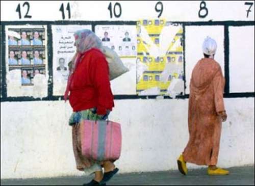 Two woman pass infront of posters on the upcoming 27 September 2002 general elections which is seen as crucial in measuring the North African kingdom's progress towards democracy 22 September 2002 in Rabat. Around 14 million voters are eligible to cast their ballots to elect 325 members of parliament from a total of 26 political parties. AFP PHOTO ABDELHAK SENNA