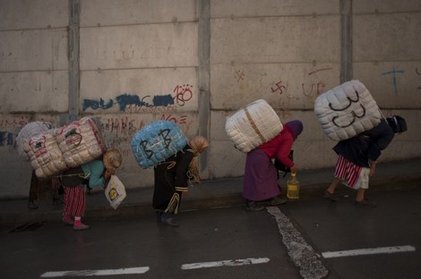 TO GO WITH AFP STORY BY ROLAND LLOYD PARRY AND INGRID BAZINET -
Women porters carry bundles on their backs for transport across the El Tarajal boarder separating Morocco and Spain's North African enclave of Ceuta, in Ceuta on December 4, 2014. Unemployment among Ceuta and Melilla's native workforce is more than 30 percent -- among the highest rates in Spain. Meanwhile, authorities say some 30,000 Moroccan traders and menial workers cross into each territory every day. AFP PHOTO / JORGE GUERRERO
