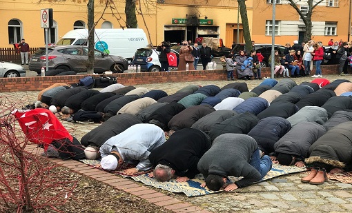 People pray near a mosque after it was destroyed by a fire in Berlin, Germany, March 11, 2018. REUTERS/Inke Kappeler